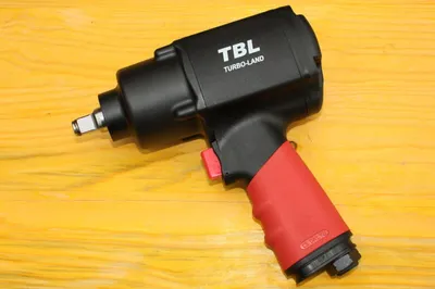 A black and red pneumatic impact wrench is placed on a wooden surface.