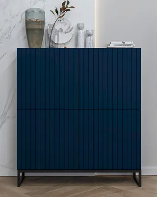 A dark blue cabinet with a fluted front stands against a marble-patterned wall.
