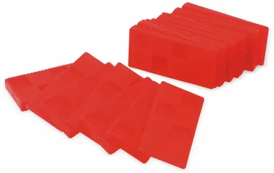 A group of red plastic shims are arranged on a white background. Some are fanned out in the foreground, while a stack of them is in the background.