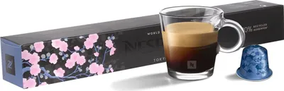 A Nespresso coffee capsule box, a glass of espresso, and a single coffee capsule.