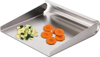 A stainless steel vegetable scoop with chopped zucchini and sliced carrots on it.