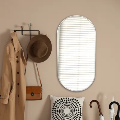 A hallway vignette featuring a mirror, coat rack with a trench coat and hat, and a decorative pillow.