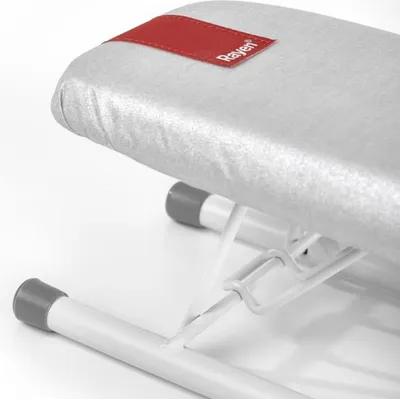 A close-up view of a small ironing board with a red brand tag.