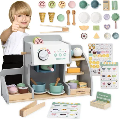 A child is giving a thumbs up next to a wooden coffee and ice cream bar playset.