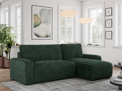 A modern living room with a green cord sofa, plants, and artwork.