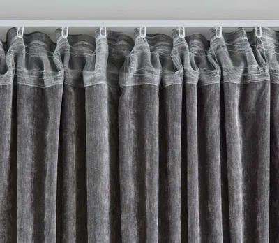 A close-up view of dark gray curtains hanging from a white curtain rod.