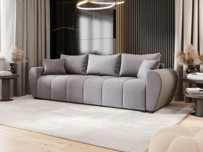 A modern living room with a large gray sofa, decorative pillows, and a rug.