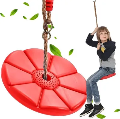 A young boy is sitting on a red disc swing, which is hanging from a rope.