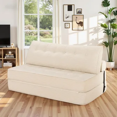 A cream-colored convertible sofa bed is shown in a living room setting with a window and artwork in the background.