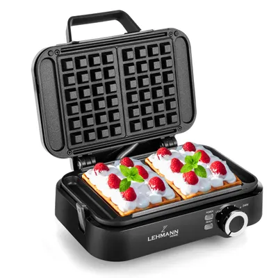 A black waffle maker with two waffles topped with cream and raspberries inside.