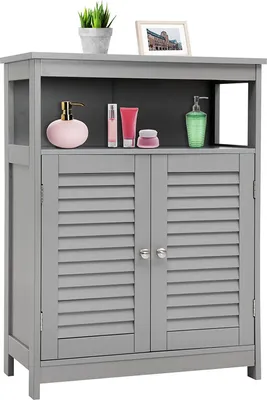 A gray bathroom cabinet with two louvered doors and an open shelf above, displaying various toiletries and a small potted plant.