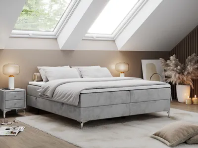 A bedroom with a bed, nightstand, and decorative items, illuminated by natural light from skylights.