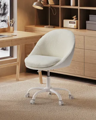A close-up of a cream-colored office chair with a fluffy texture, placed on a beige carpet in front of a wooden desk and cabinet.