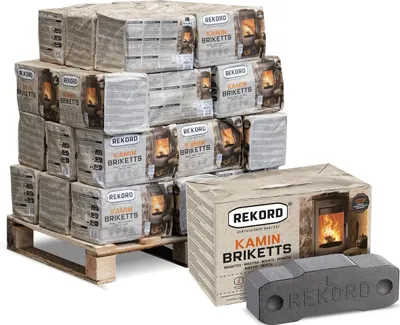 A pallet stacked with packages of Rekord Kamin Briketts, with a single briquette and a box in the foreground.
