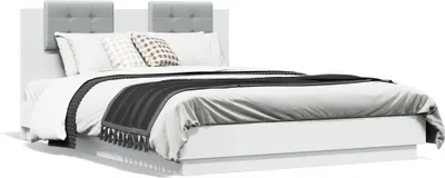 A white bed frame with a gray upholstered headboard, white bedding, and a black and gray throw blanket.