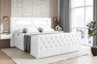 A white upholstered bed with LED lighting in the headboard, set in a bedroom with a window and decorative wall panels.