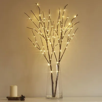 LED branches in a vase on a shelf with a candle.