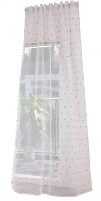 A sheer curtain with pompom details hanging in front of a window.