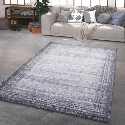 A living room with a sofa, rug, and some weights.