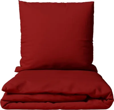 A folded red duvet and a red pillow are stacked on top of each other against a white background.