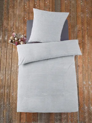 A top-down view of a bedding set laid out on a wooden floor.