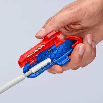 A hand holding a wire stripper tool with a white wire inserted.
