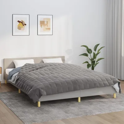 A bedroom scene with a bed, blanket, and artwork.