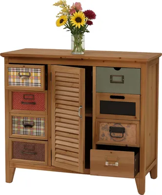 A wooden apothecary cabinet with multiple drawers and a louvered door, displaying a vase of flowers on top.