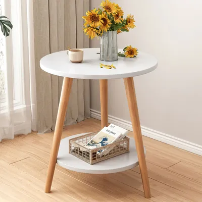 A small round side table with sunflowers and a mug on top, and a basket with magazines on the lower shelf.