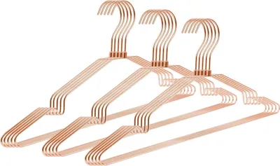 A group of rose gold metal hangers on a white background.