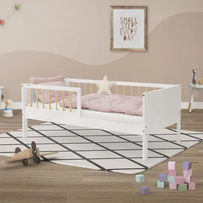 A child's bed with bedding and a small wooden airplane on a rug.