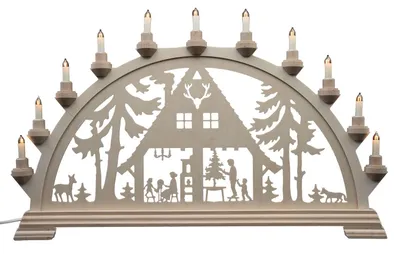 Ein traditioneller Schwibbogen aus dem Erzgebirge zeigt ein Waldhaus mit Tieren und Bäumen im Scherenschnittstil beleuchtet von mehreren kleinen Kerzen die eine gemütliche Atmosphäre schaffen