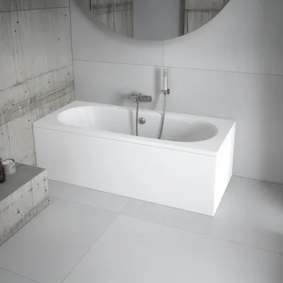 A modern bathroom with a white bathtub, concrete-effect wall tiles, and light gray floor tiles.