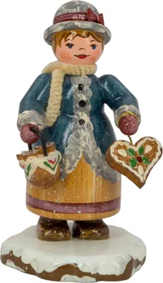 Eine fröhliche Holzfigur in winterlicher Kleidung hält ein Lebkuchenherz in der einen Hand und einen Korb in der anderen während sie auf einem schneebedeckten Sockel steht und ein warmes Lächeln zeigt