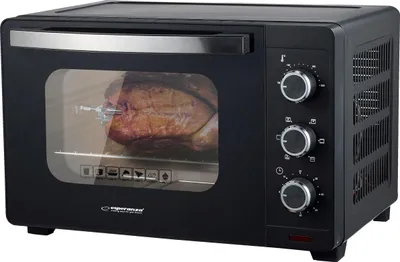 A black mini oven with a roast chicken inside, shown from a front-side angle.
