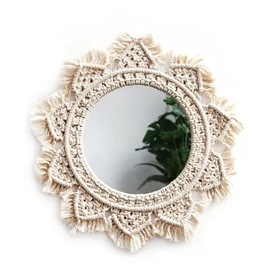 A round macrame mirror with fringe detail on a white background.