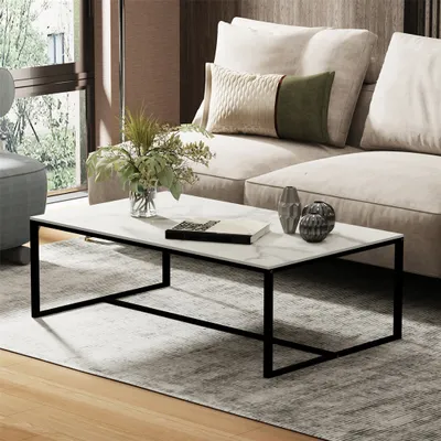 A modern living room scene featuring a marble-top coffee table with a black metal frame, placed on a rug in front of a sofa.