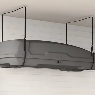 A gray roof box is suspended from the ceiling by straps.