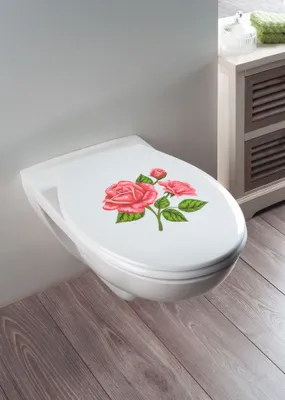 A white toilet seat with a rose design is shown in a bathroom setting.