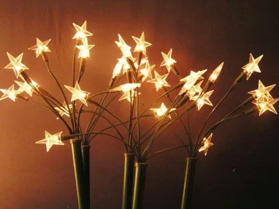 A cluster of star-shaped LED lights on green stems against a dark brown background.