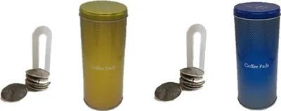 Two cylindrical coffee pad containers, one gold and one blue, are displayed with stacks of coffee pads and a white holder beside each.