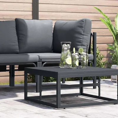 An outdoor patio scene with a gray sofa and a dark gray coffee table with drinks.
