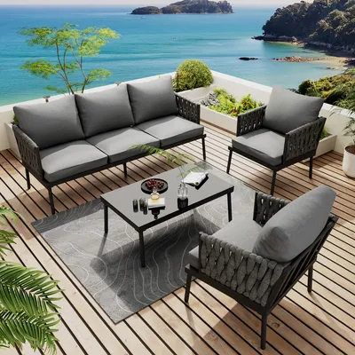 A patio furniture set on a wooden deck overlooking the ocean.
