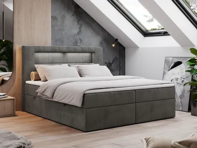 A modern bedroom with a boxspring bed under a slanted ceiling with skylights.
