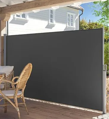 A retractable side awning is extended on a wooden deck next to a house, with outdoor furniture visible.