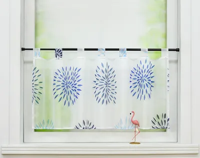 A short curtain with a blue floral pattern hangs in a window, with a small pink flamingo figurine on the windowsill.