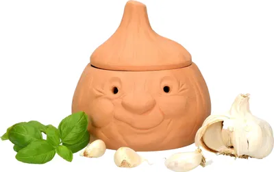 A terracotta garlic keeper shaped like a smiling garlic bulb, with basil leaves and garlic cloves in front of it.