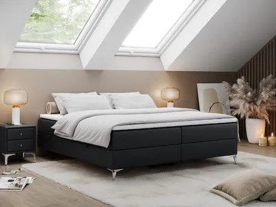 A bedroom with a bed, nightstands, and lamps under skylights.