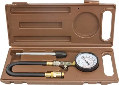A compression tester kit is neatly arranged in its brown plastic case.