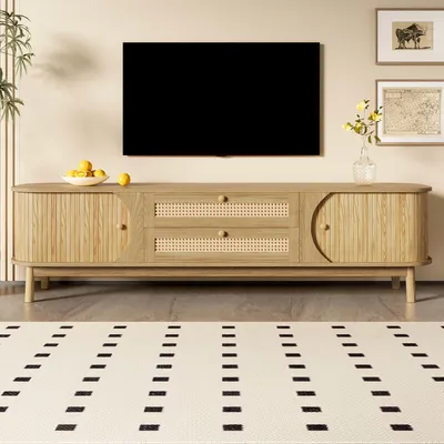 A TV stand with a TV mounted above it, in a living room setting with a rug and artwork on the wall.